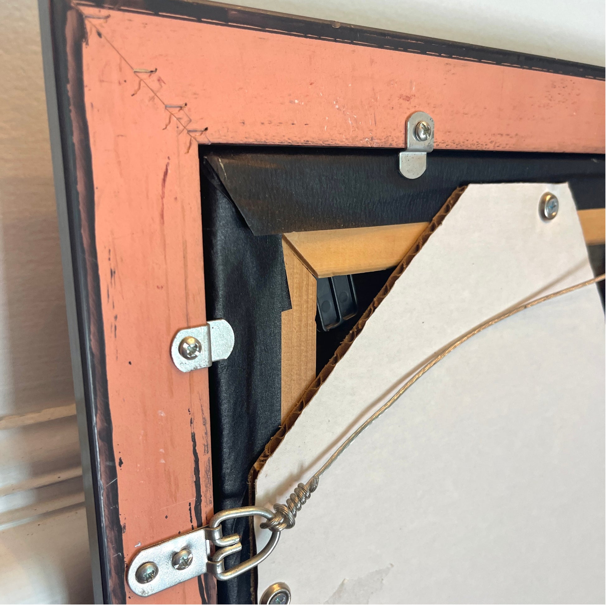 Close-up of the back corner of a framed picture, showing re-stretched painting.